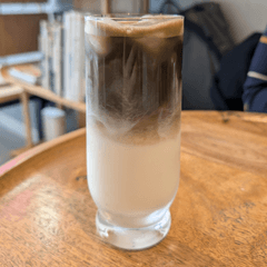 Es hojicha latte berlapis teh sangrai cokelat di atas susu dalam gelas tinggi
