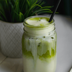 Foto es matcha latte dalam toples kaca, susu dan matcha berlapis, dengan sedotan