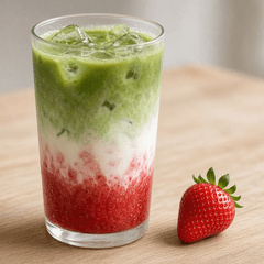 Strawberry matcha latte berlapis stroberi, susu, dan matcha dengan es, ditemani sebuah stroberi